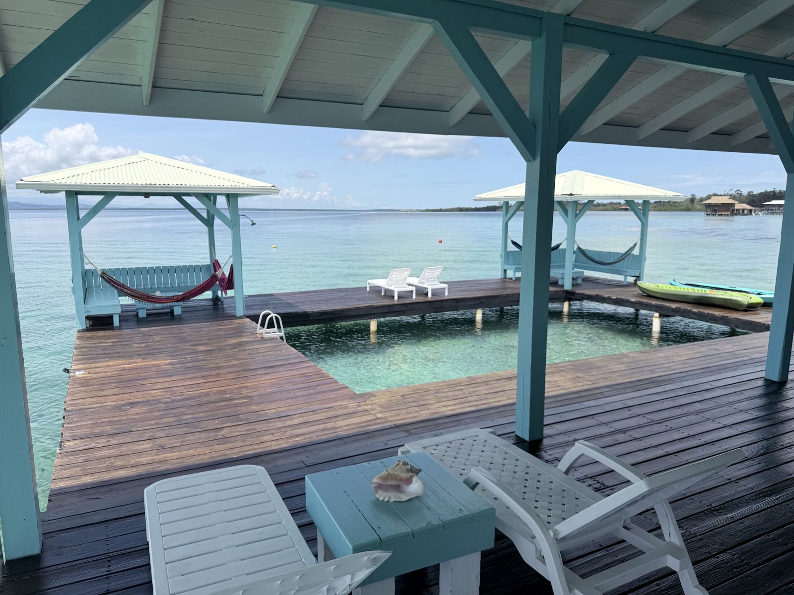 Covered deck at Casa Clearwater with loungers, hammock cabanas, kayaks and the natural saltwater pool