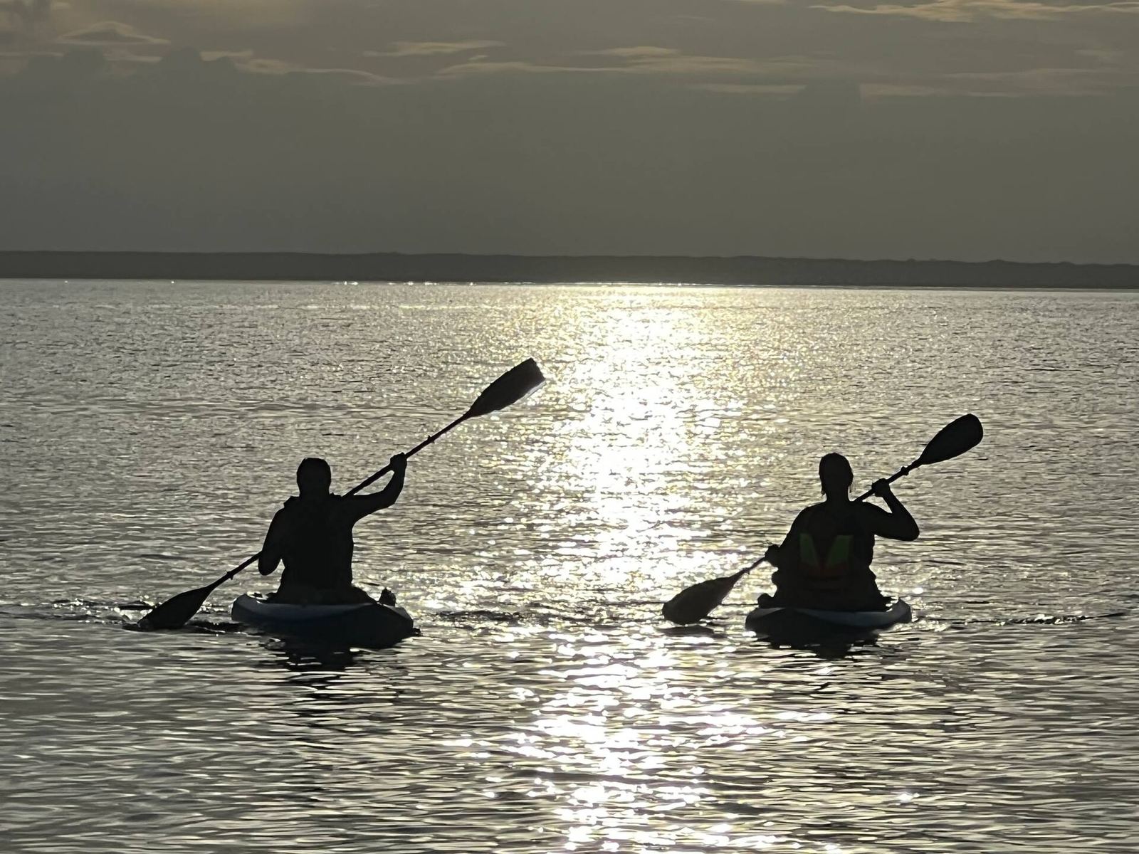 Two guests kayaking on the calm water at sunset