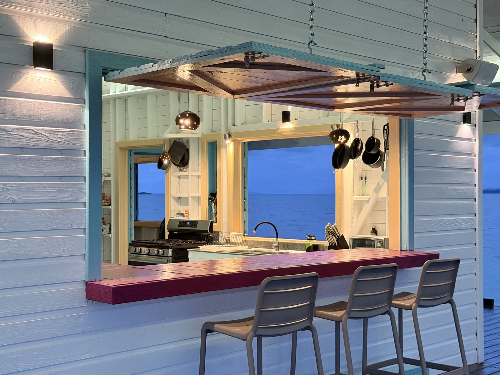 Kitchen pass-through bar window with stools and the sea behind