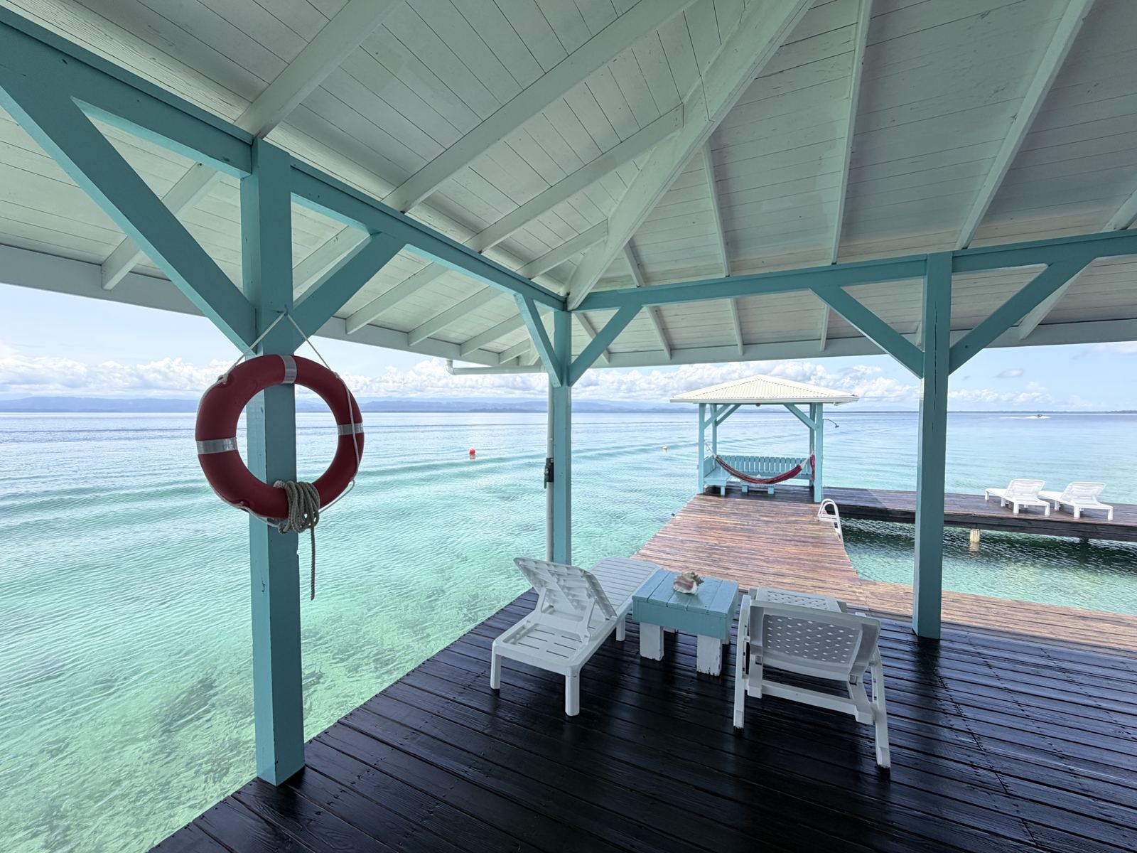 Shaded deck at Casa Clearwater looking out over clear Caribbean water to a hammock cabana